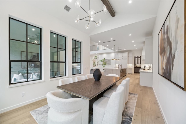 dining room featuring light hardwood / wood-style floors, sink, a notable chandelier, and vaulted ceiling with beams