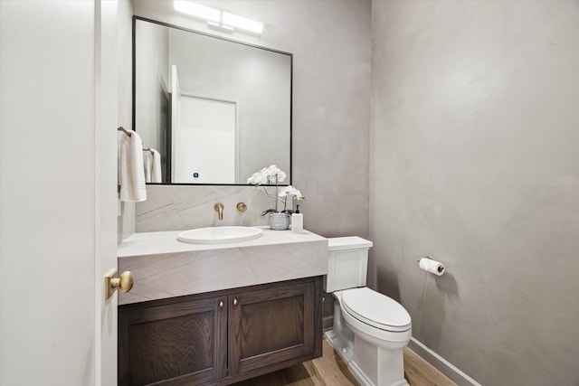 bathroom with tasteful backsplash, toilet, wood-type flooring, and vanity