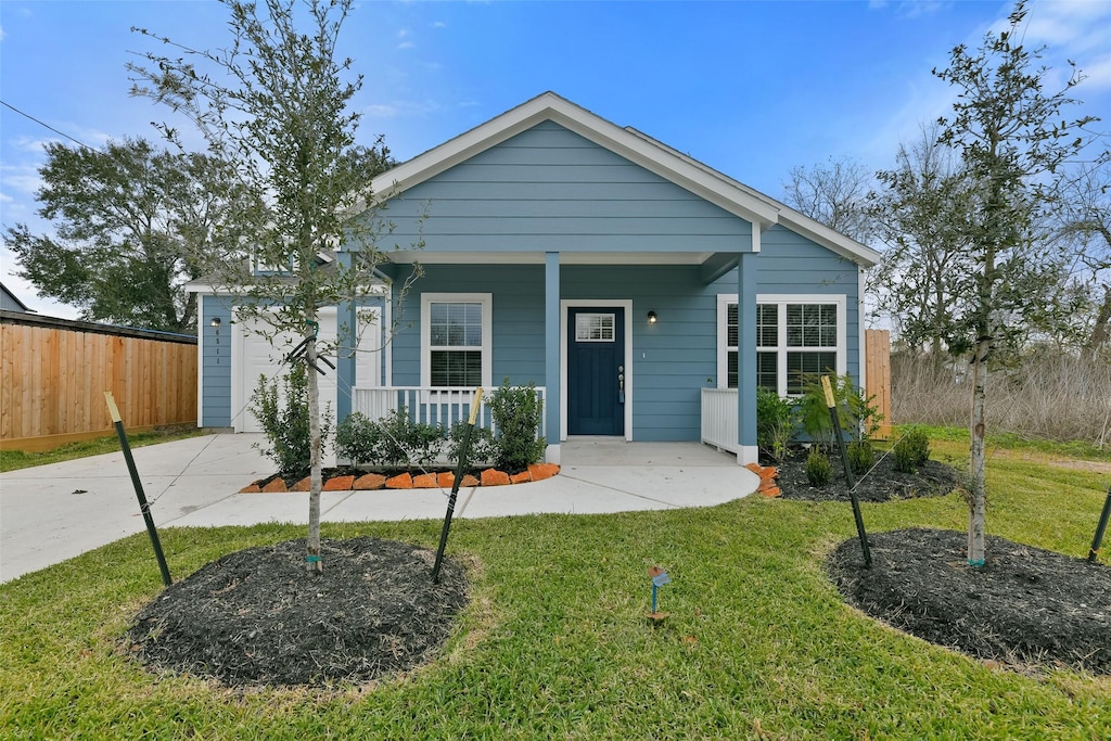 view of front of home featuring a front lawn, covered porch, and a garage