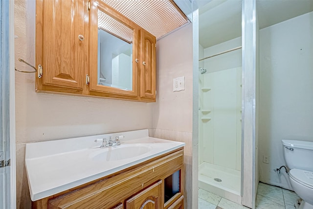 bathroom featuring tile patterned flooring, toilet, walk in shower, and vanity