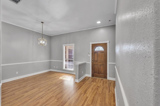 foyer entrance featuring ornamental molding, wood-type flooring, and a notable chandelier