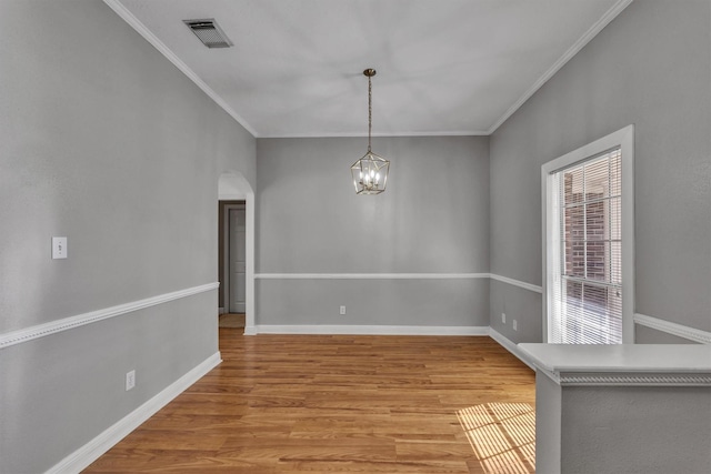 unfurnished dining area with crown molding, an inviting chandelier, and light hardwood / wood-style floors