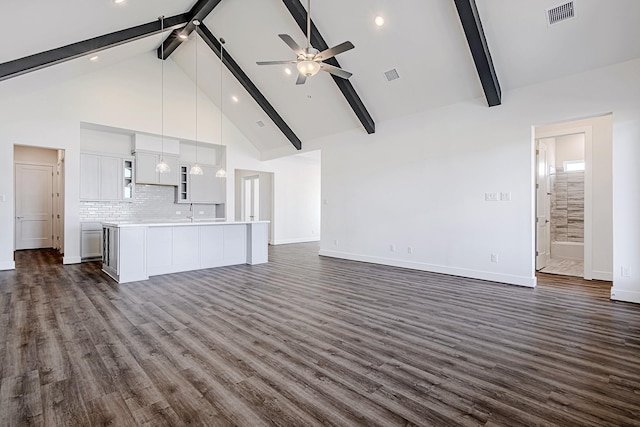 unfurnished living room with ceiling fan, dark hardwood / wood-style flooring, beam ceiling, and high vaulted ceiling