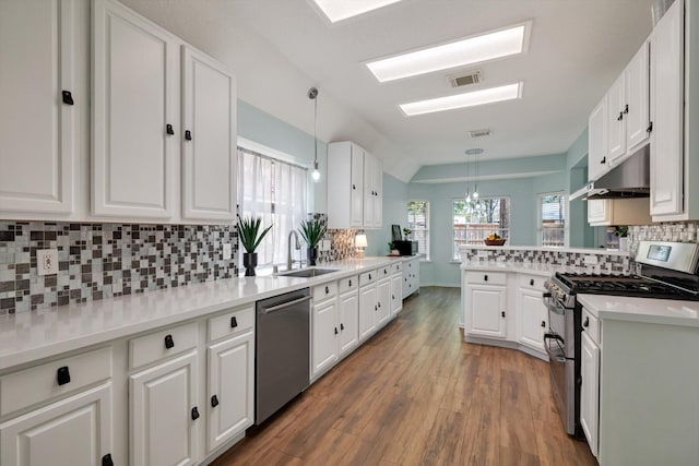 kitchen featuring pendant lighting, white cabinetry, stainless steel appliances, sink, and kitchen peninsula