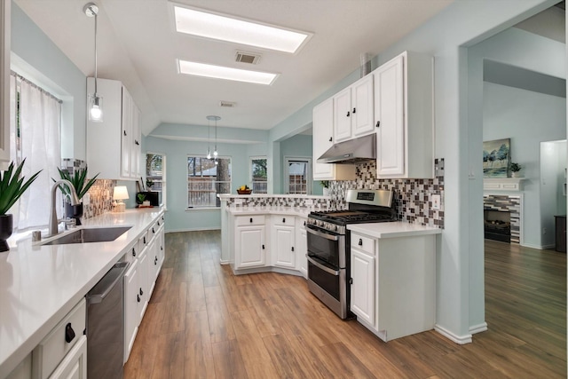 kitchen with stainless steel appliances, white cabinetry, decorative light fixtures, and sink