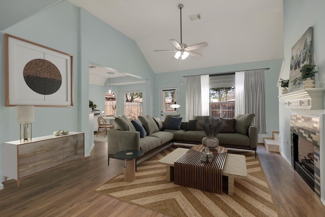 living room featuring vaulted ceiling, dark hardwood / wood-style flooring, a healthy amount of sunlight, and a fireplace