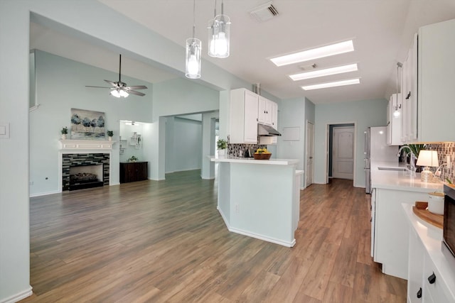 kitchen featuring ceiling fan, a fireplace, pendant lighting, decorative backsplash, and white cabinetry