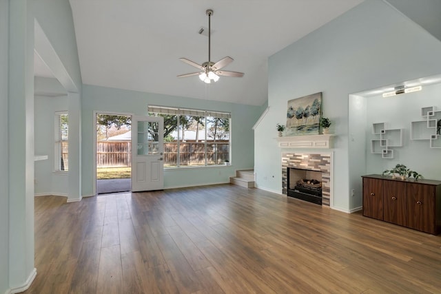 unfurnished living room with ceiling fan, high vaulted ceiling, a fireplace, and hardwood / wood-style flooring