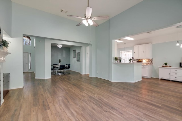 unfurnished living room featuring high vaulted ceiling, ceiling fan, and hardwood / wood-style flooring