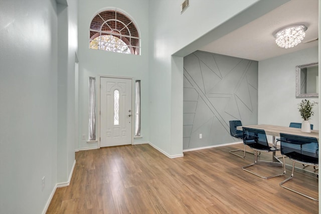 foyer with a high ceiling, wood-type flooring, and a notable chandelier