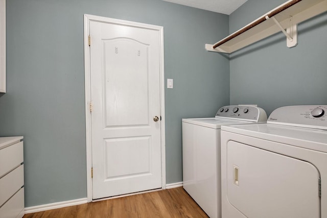 clothes washing area with light hardwood / wood-style floors and washing machine and clothes dryer