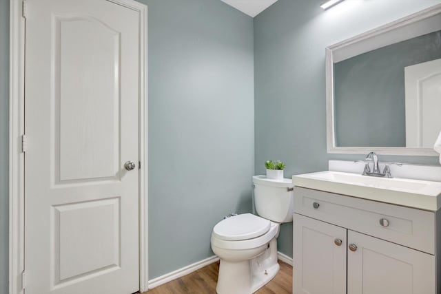 bathroom with toilet, vanity, and wood-type flooring