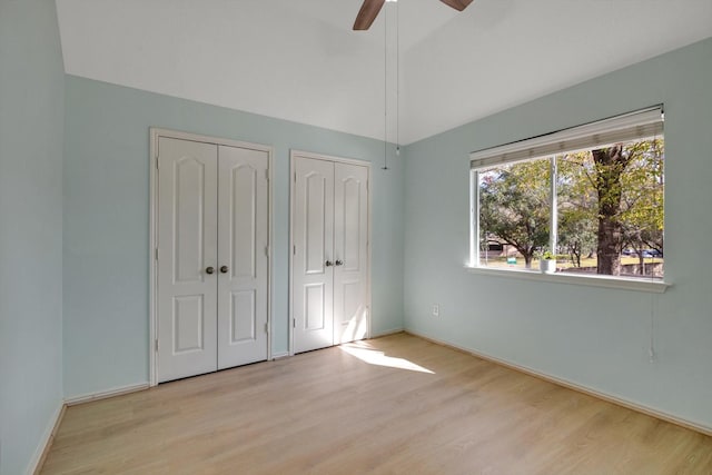 unfurnished bedroom featuring light wood-type flooring, ceiling fan, and two closets