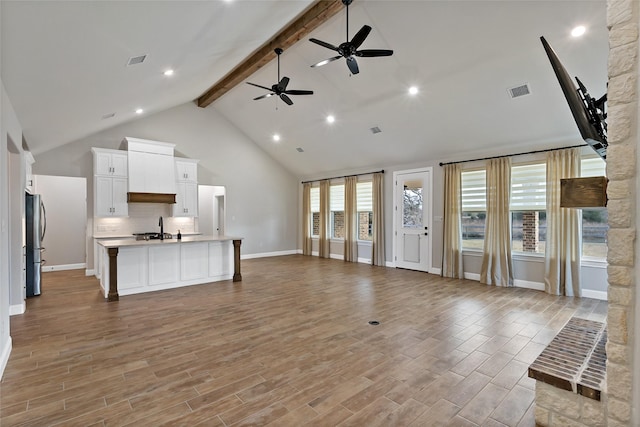 living room featuring ceiling fan, sink, high vaulted ceiling, and beam ceiling