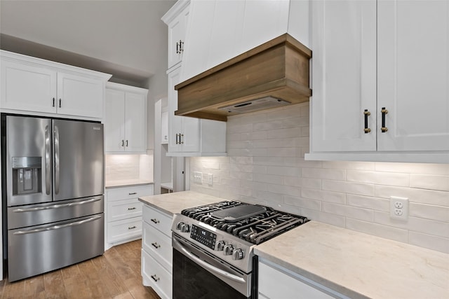 kitchen featuring premium range hood, stainless steel appliances, decorative backsplash, light wood-type flooring, and white cabinets