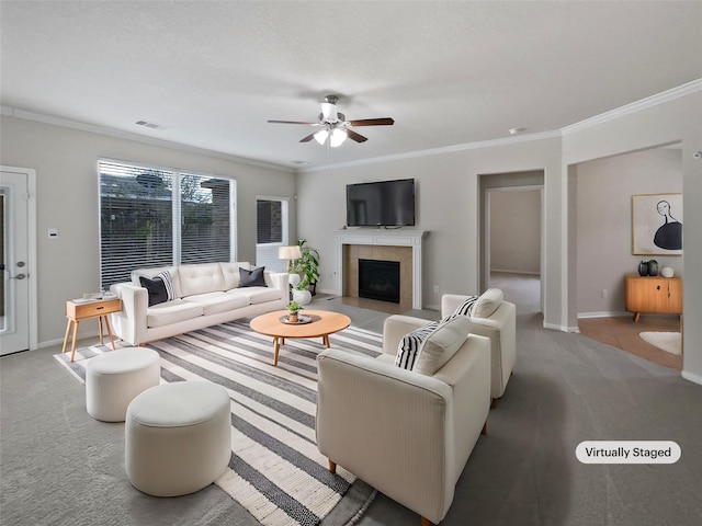 carpeted living room with ceiling fan, a fireplace, and crown molding