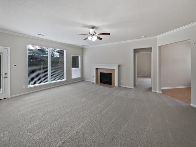 unfurnished living room featuring a tiled fireplace, ceiling fan, crown molding, light carpet, and a textured ceiling