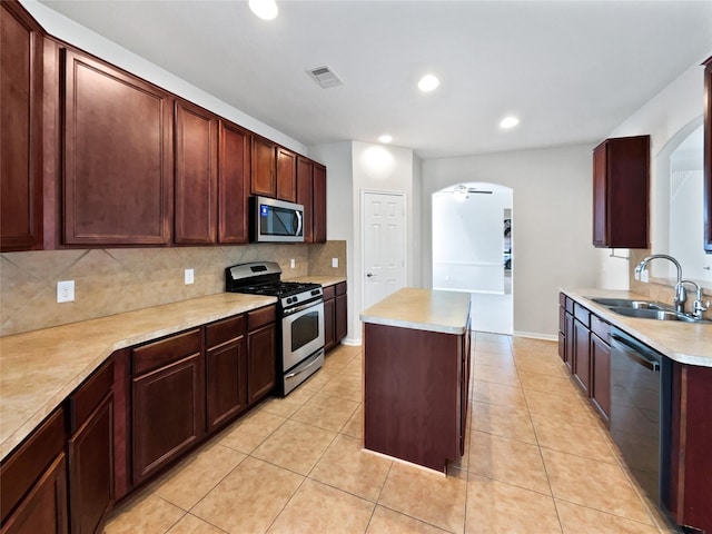 kitchen featuring appliances with stainless steel finishes, a kitchen island, sink, ceiling fan, and light tile patterned floors