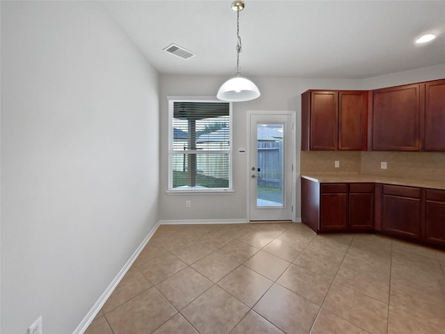 kitchen featuring light tile patterned floors, backsplash, and decorative light fixtures