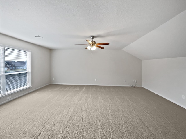 interior space with carpet, vaulted ceiling, a textured ceiling, and ceiling fan