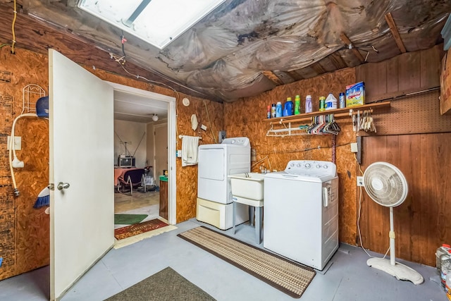 laundry area featuring washer and dryer, sink, and wooden walls