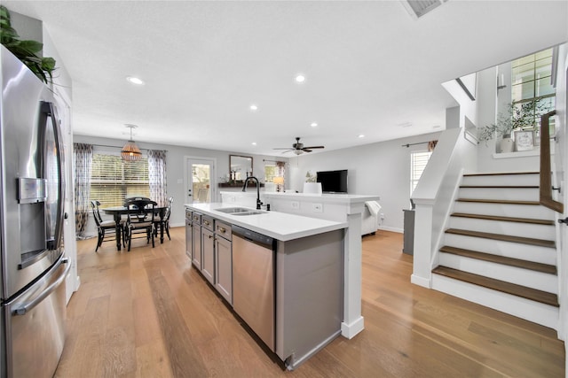 kitchen with appliances with stainless steel finishes, sink, hanging light fixtures, a kitchen island with sink, and ceiling fan