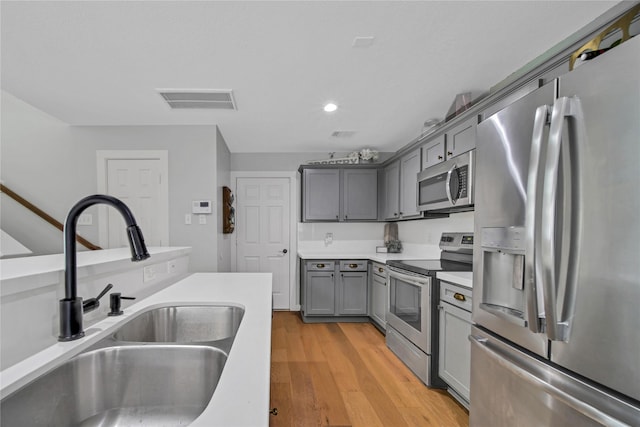 kitchen featuring light hardwood / wood-style floors, sink, appliances with stainless steel finishes, and gray cabinets