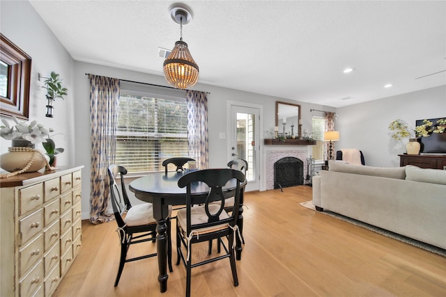 dining area with light hardwood / wood-style floors and a brick fireplace