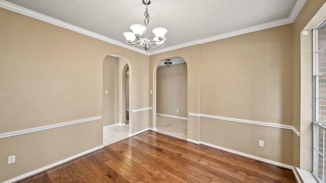 empty room with hardwood / wood-style floors, crown molding, and a chandelier