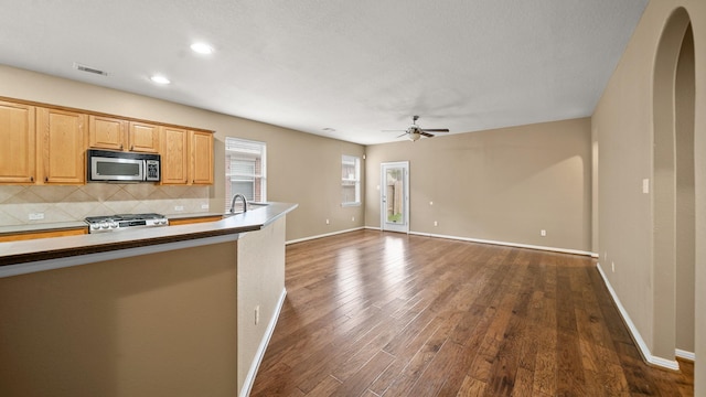 kitchen featuring decorative backsplash, sink, dark hardwood / wood-style floors, ceiling fan, and stove