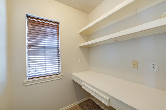 unfurnished office with carpet, a textured ceiling, and baseboards