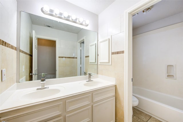 full bath with toilet, tile patterned flooring, tile walls, and a sink