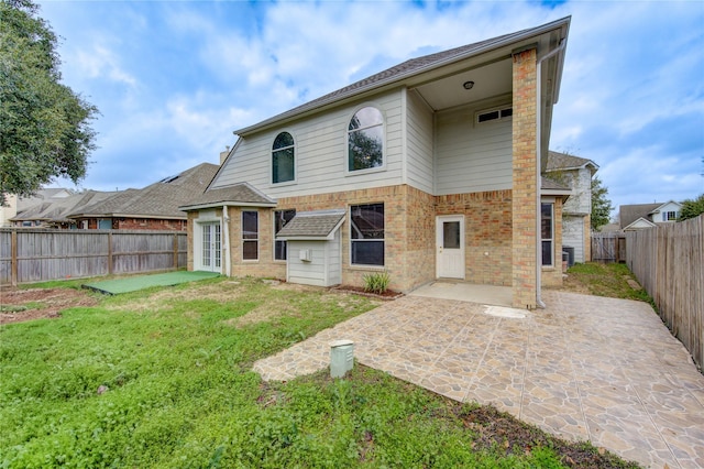 back of property with a patio, a fenced backyard, brick siding, a yard, and french doors