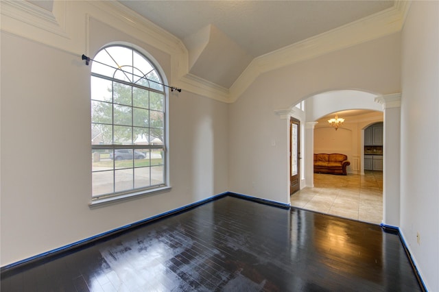 spare room featuring light wood finished floors, plenty of natural light, arched walkways, and crown molding