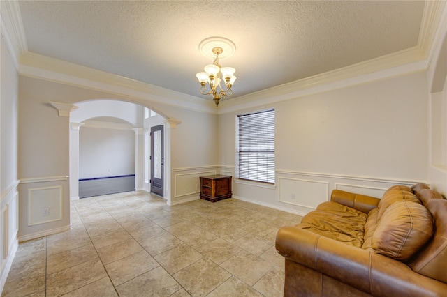 living area with ornamental molding, arched walkways, a decorative wall, and ornate columns