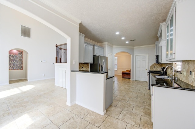 kitchen with dark countertops, visible vents, arched walkways, and stainless steel appliances