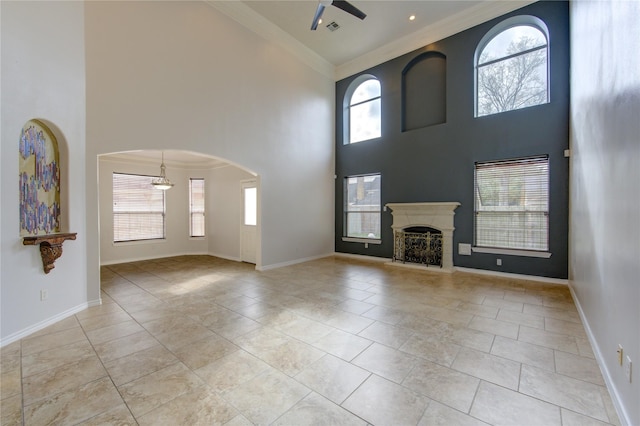 unfurnished living room featuring a fireplace with raised hearth, baseboards, arched walkways, and crown molding