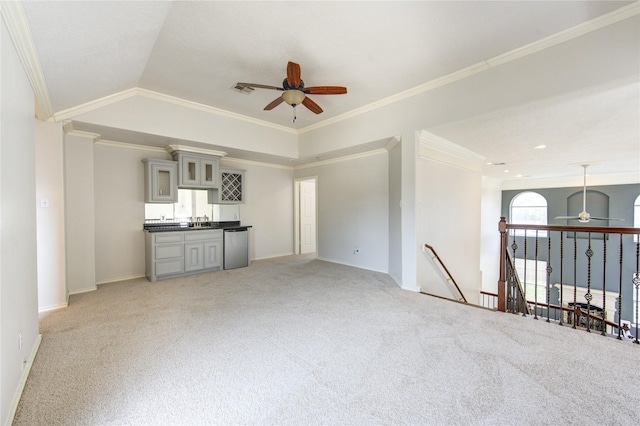 unfurnished living room featuring carpet floors, indoor wet bar, visible vents, ornamental molding, and ceiling fan