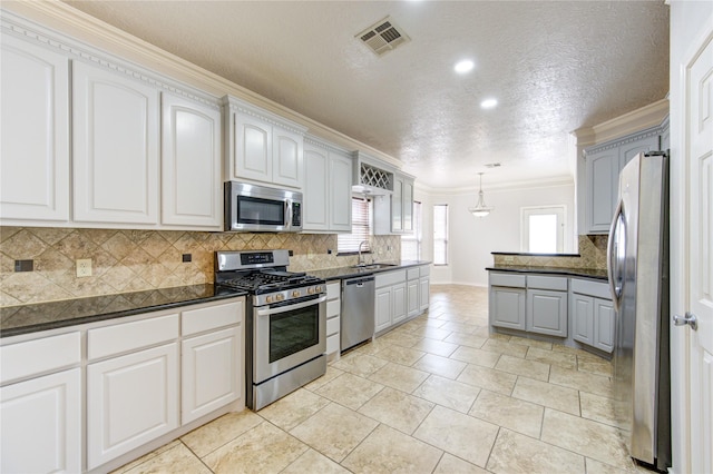 kitchen featuring stainless steel appliances, a sink, visible vents, white cabinetry, and hanging light fixtures