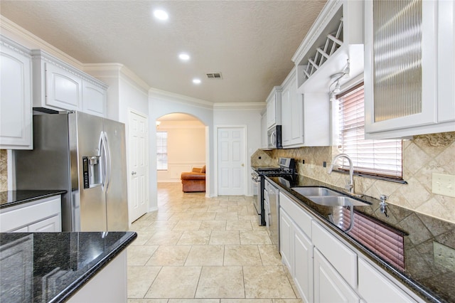 kitchen with dark stone countertops, appliances with stainless steel finishes, white cabinets, and a sink