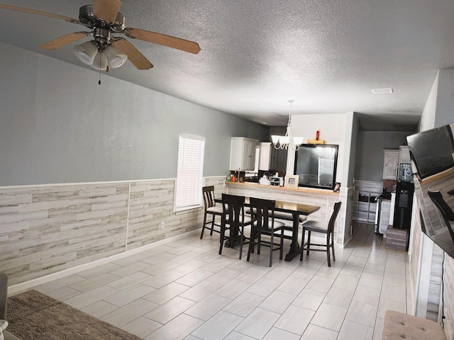 dining space with ceiling fan with notable chandelier and a textured ceiling