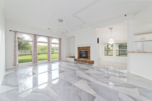 unfurnished living room featuring a stone fireplace, crown molding, and decorative columns