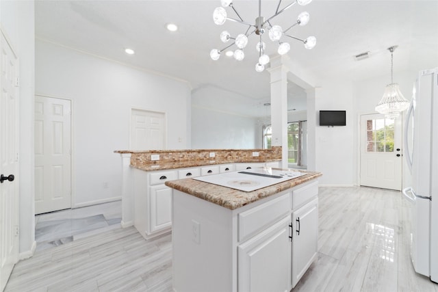 kitchen featuring white cabinets, a center island, decorative light fixtures, white refrigerator, and an inviting chandelier