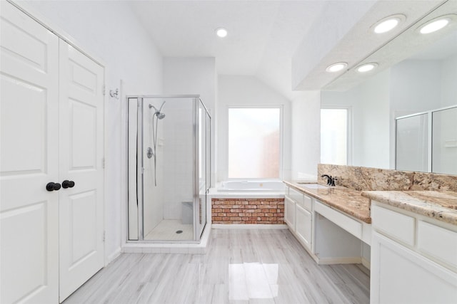 bathroom featuring hardwood / wood-style floors, vanity, lofted ceiling, and plus walk in shower