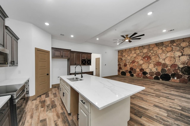 kitchen featuring white cabinetry, sink, stainless steel electric range, and an island with sink