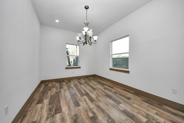 spare room featuring dark hardwood / wood-style floors and a chandelier