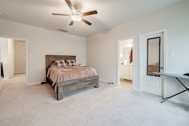 bedroom with ceiling fan, light colored carpet, and ensuite bathroom