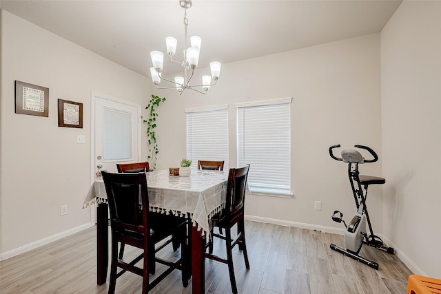 dining space featuring light wood-type flooring and a notable chandelier