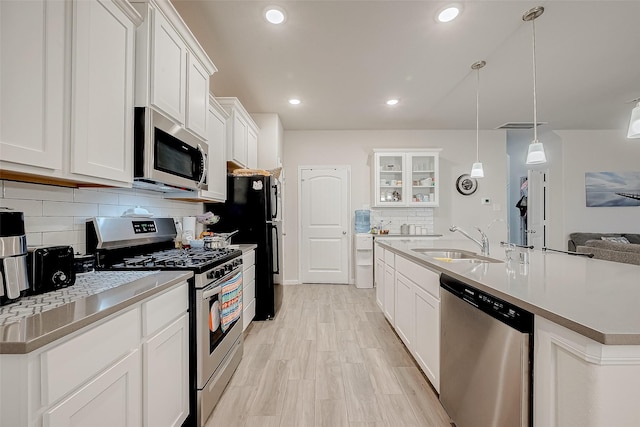 kitchen with hanging light fixtures, appliances with stainless steel finishes, sink, and white cabinetry