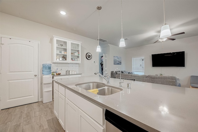 kitchen featuring hanging light fixtures, white cabinets, sink, and light hardwood / wood-style floors